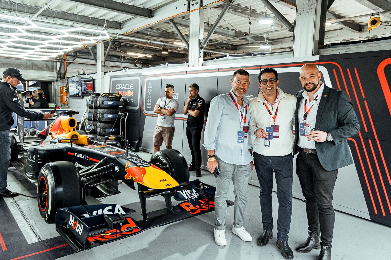 Three guests standing beside a Formula 1 car in a race garage