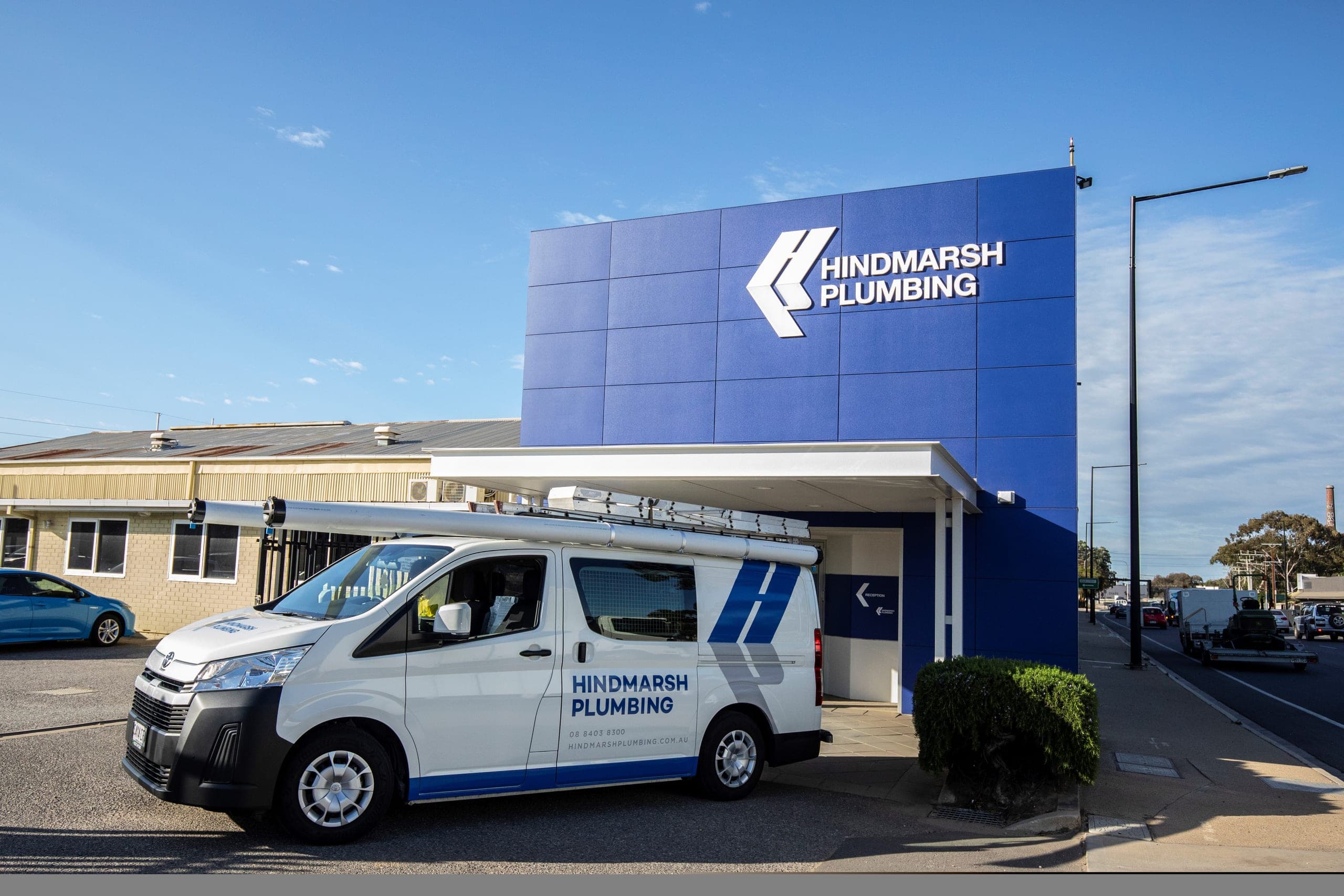 A Hindmarsh Plumbing service van parked outside the blue-clad Hindmarsh Plumbing building