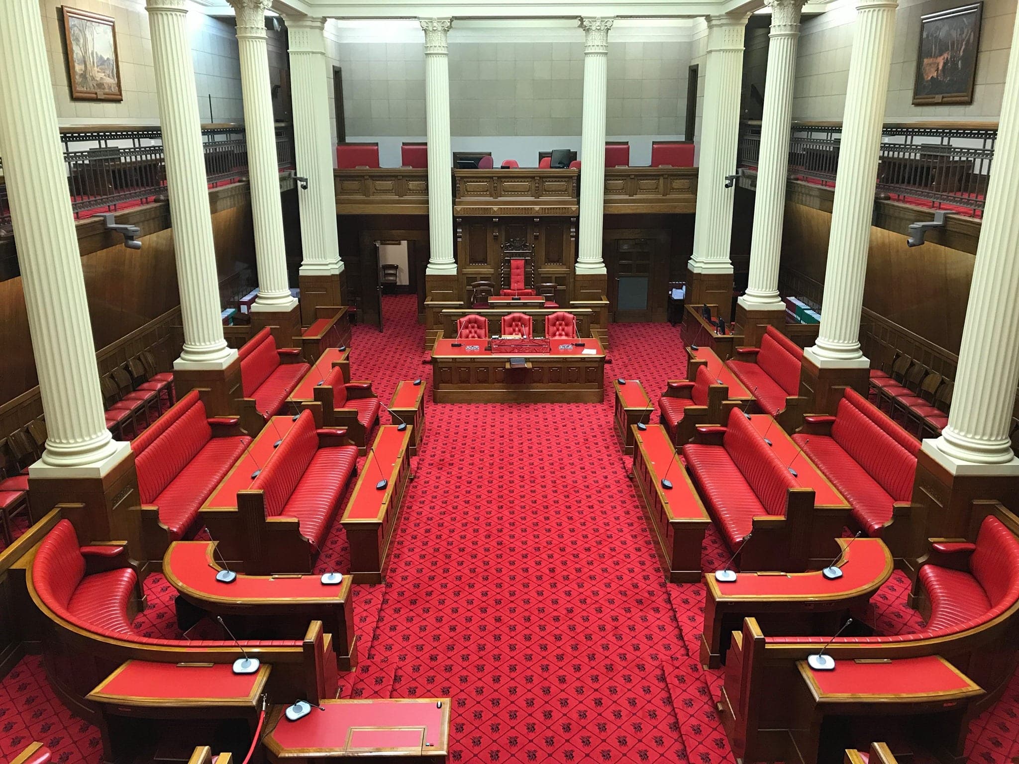 Parliamentary chamber with red leather benches, red carpet and white columns