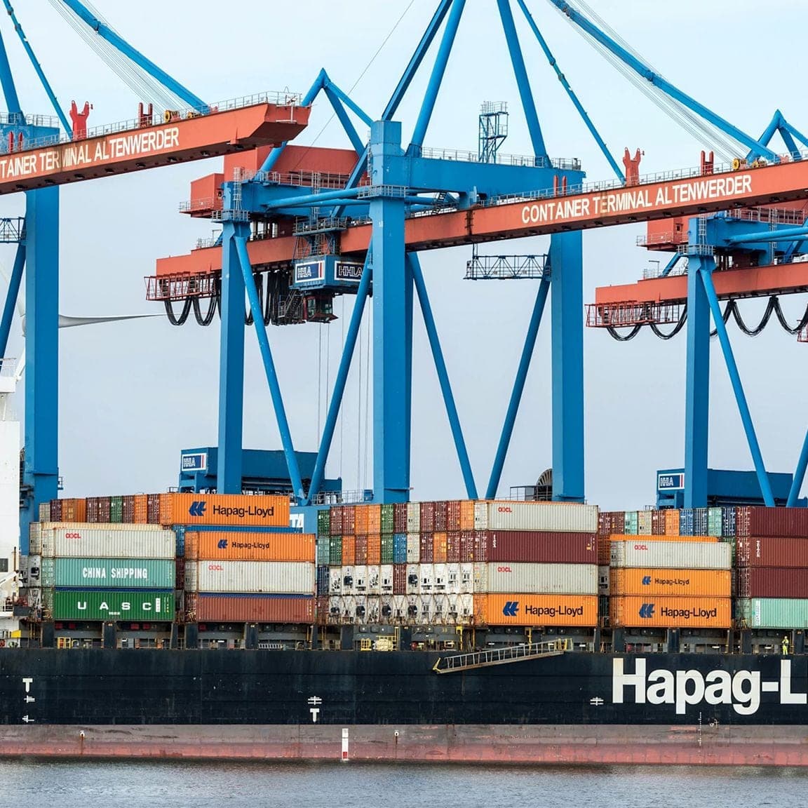 Cargo ship loaded with containers beneath large port cranes