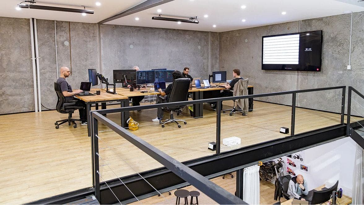 Team working at desks in an open-plan office with a mezzanine railing in the foreground