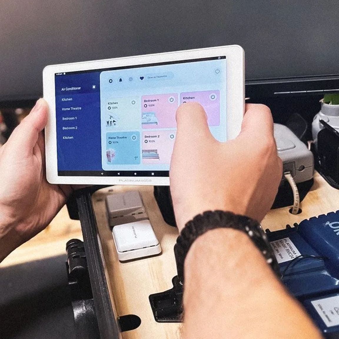 Hands holding a tablet showing a smart home control app, next to test hardware
