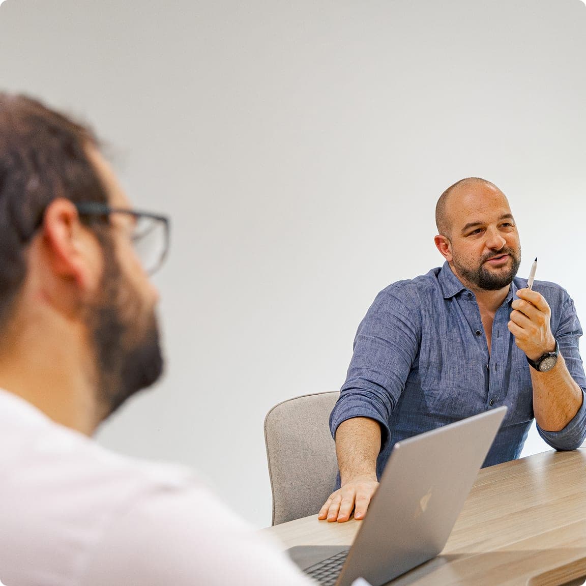 Two CodeFish team members in discussion across a meeting room table, one taking notes