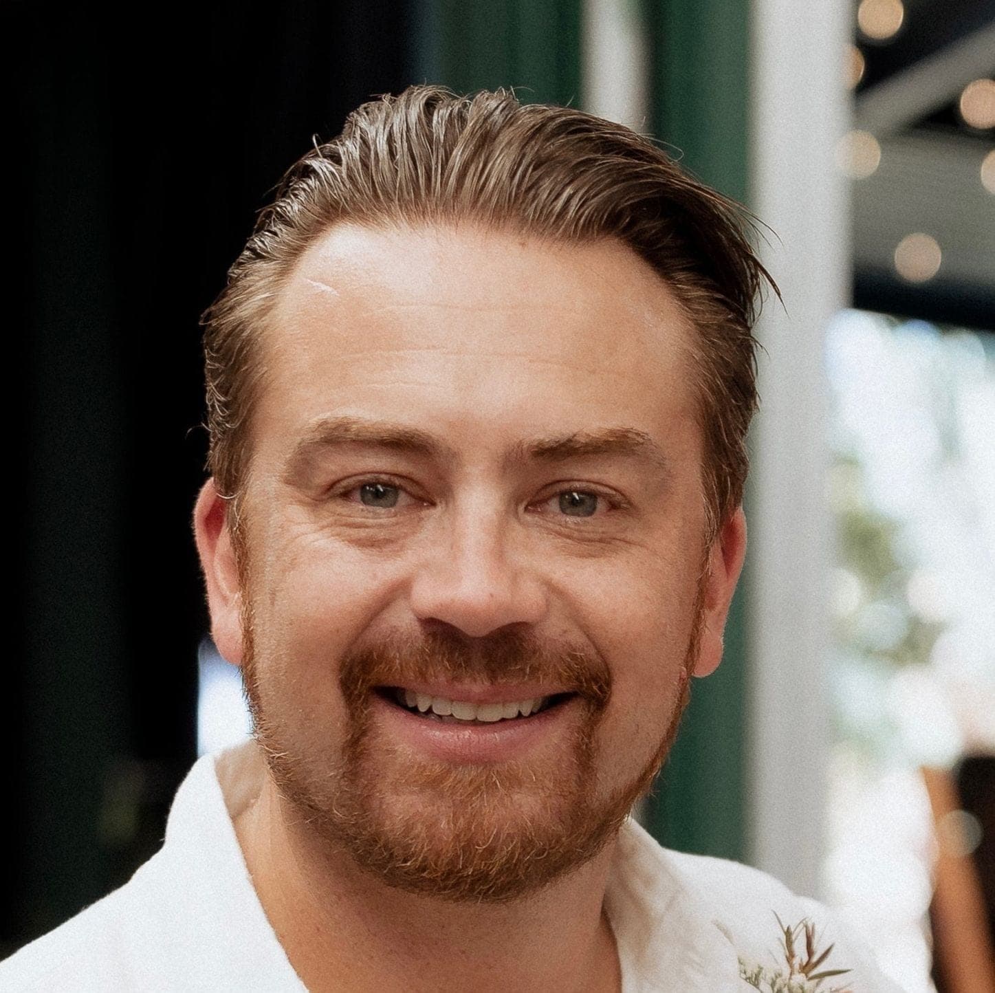 A person smiling to camera at an outdoor evening event