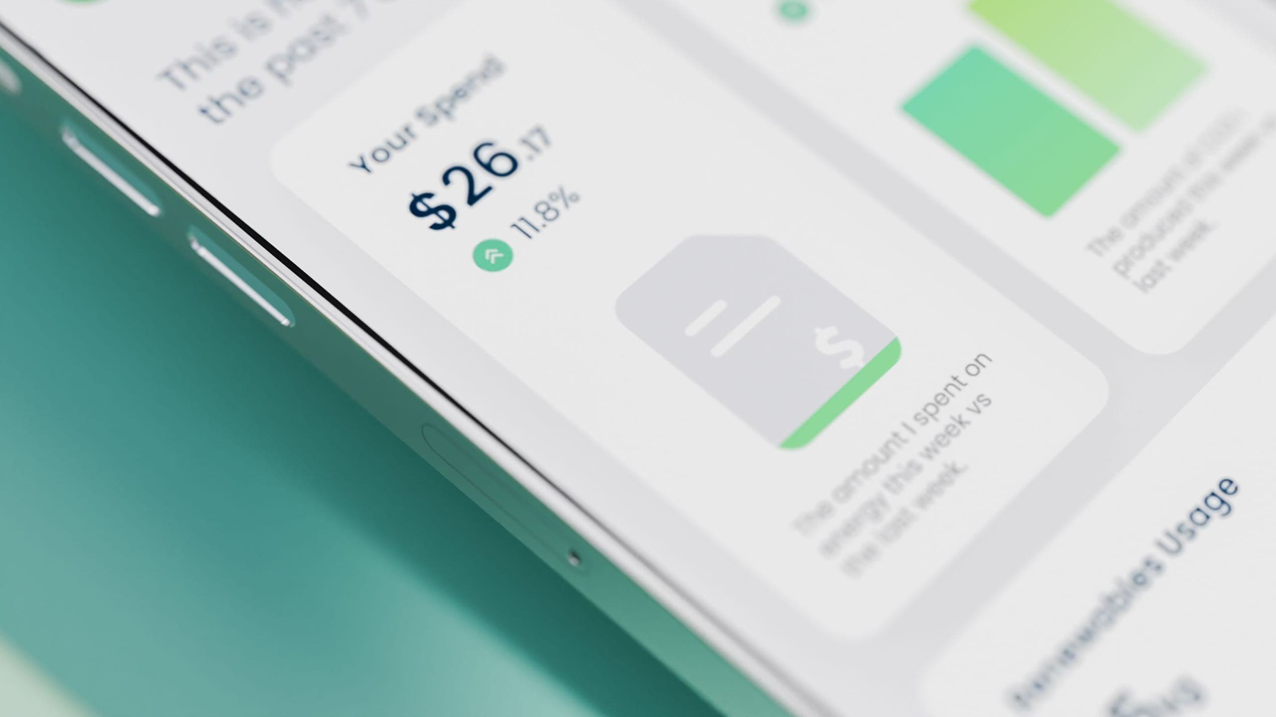 Close-up of a phone showing an energy app spend card reading $26.17, up 11.8 per cent