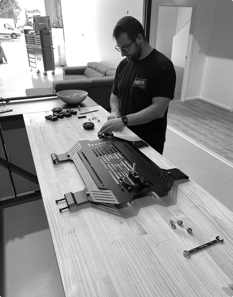 A team member assembling a slotted alloy storage panel on a workbench