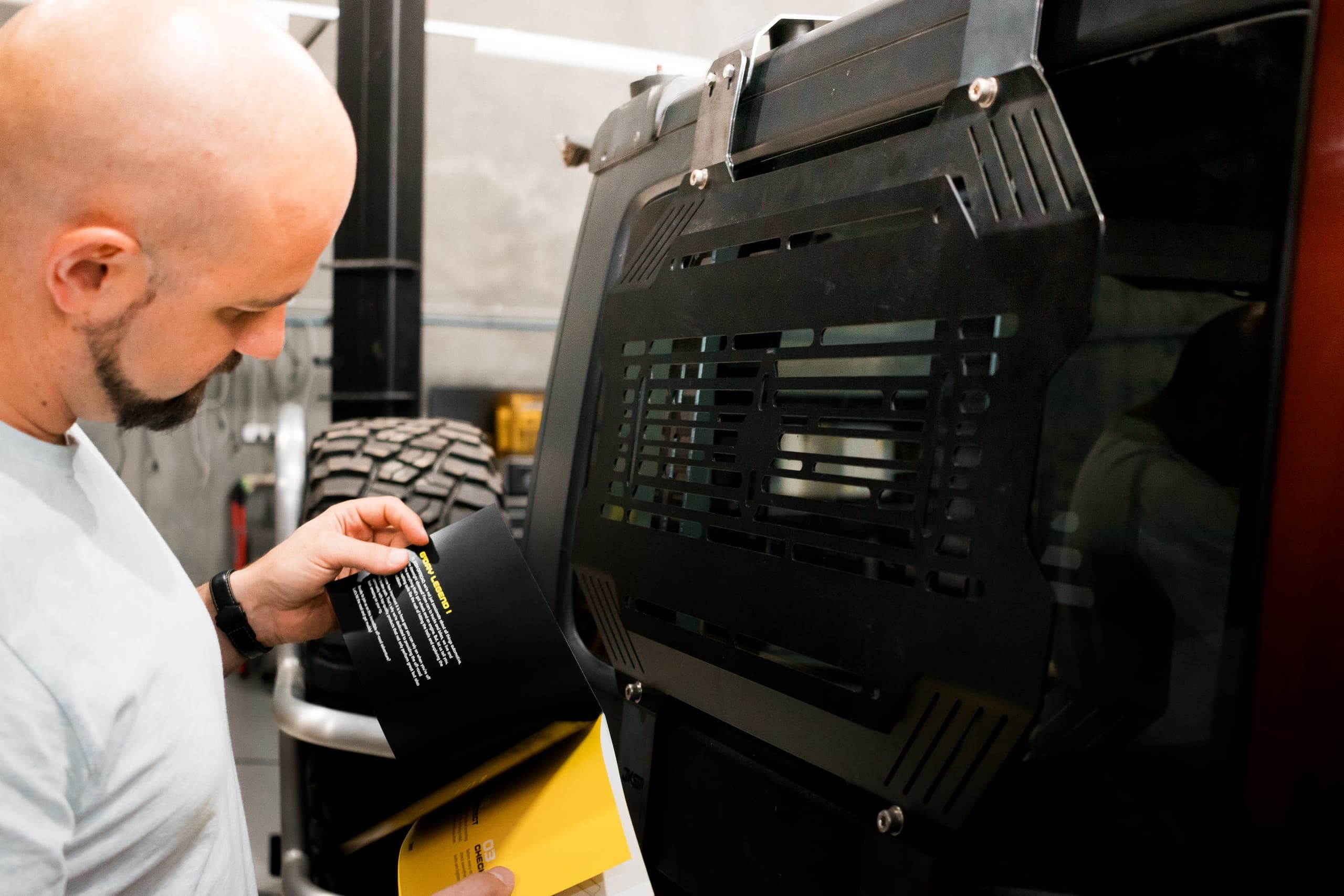 A team member reviewing printed documents beside a black storage panel fitted to a vehicle window